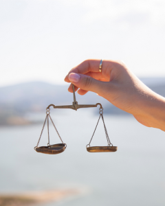 Image of a hand holding a balanced scale with water in the background.