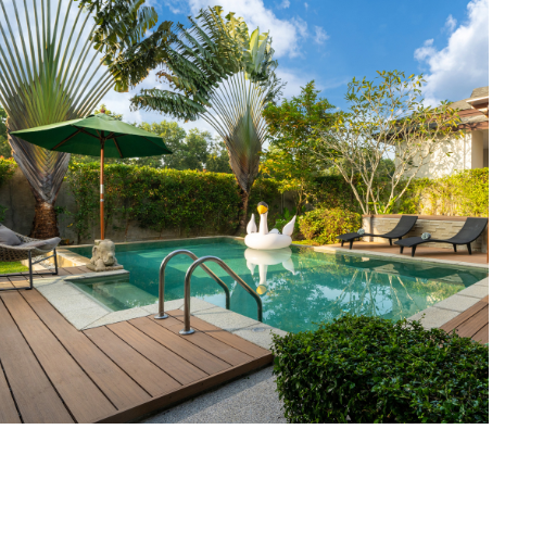 Outdoor pool with lots of greenery and shrubs surrounding it.