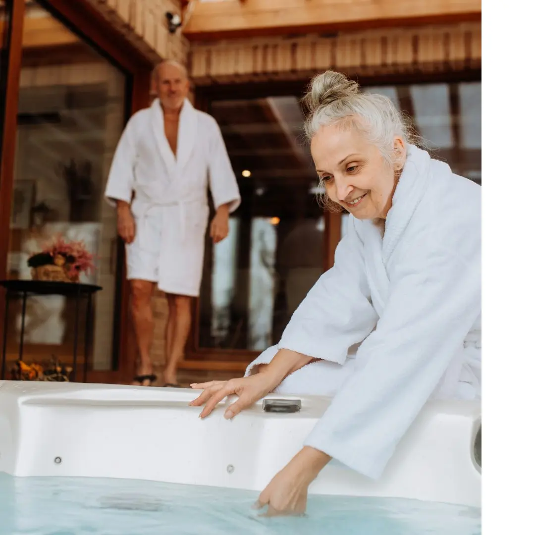 An elderly couple in white robes test out the swim spa water