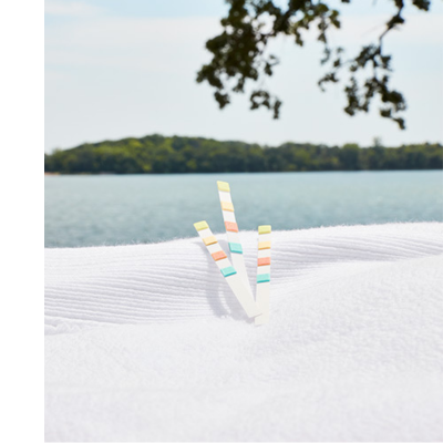 Water test strips sit on a white towel with water in the background.