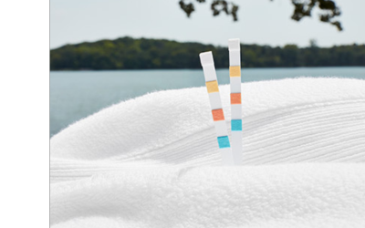 Two FROG Test Strips sit on a white towel. There is a lake with greenery in the background of the photo.