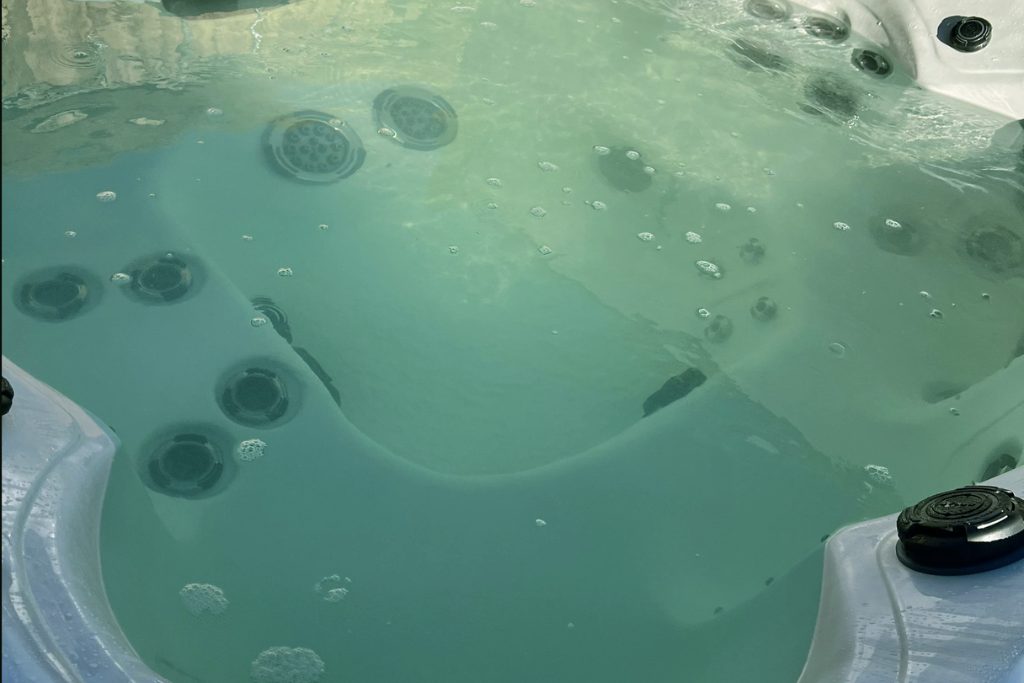 Close up image of green hot tub water that is caused by algae.
