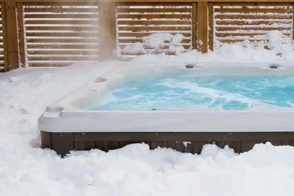 An outdoor swim spa is surrounded by snow.